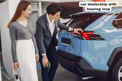 Customer testing a vehicle console inside a modern car dealership with hearing loop signage clearly visible at the information desk