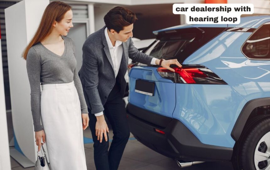 Customer testing a vehicle console inside a modern car dealership with hearing loop signage clearly visible at the information desk