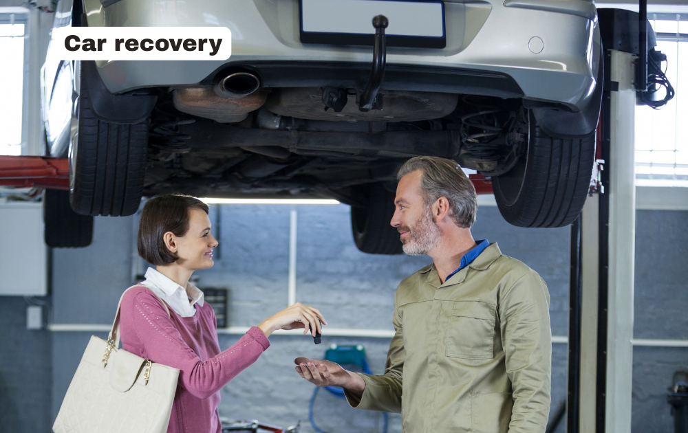 Professional car recovery flatbed tow truck transporting a broken down vehicle safely on a UK road